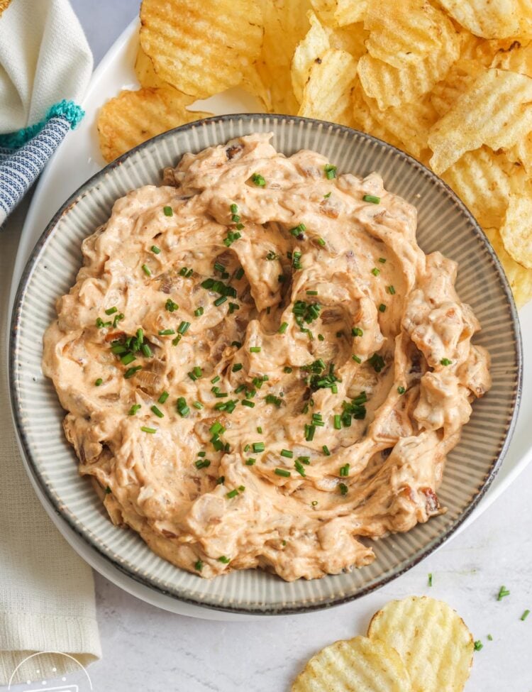 a platter of potato chips with a large bowl of homemade caramelized onion dip on the left side.