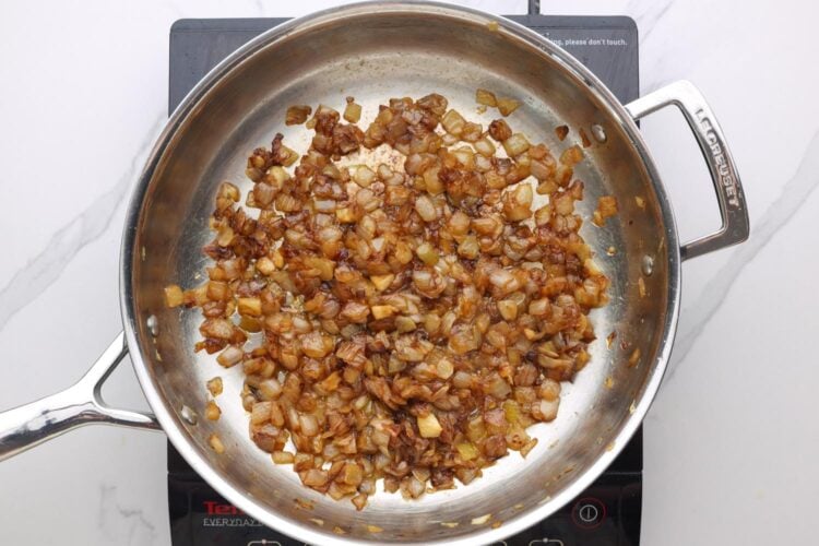 caramelized diced onions in a stainless steel frying pan.