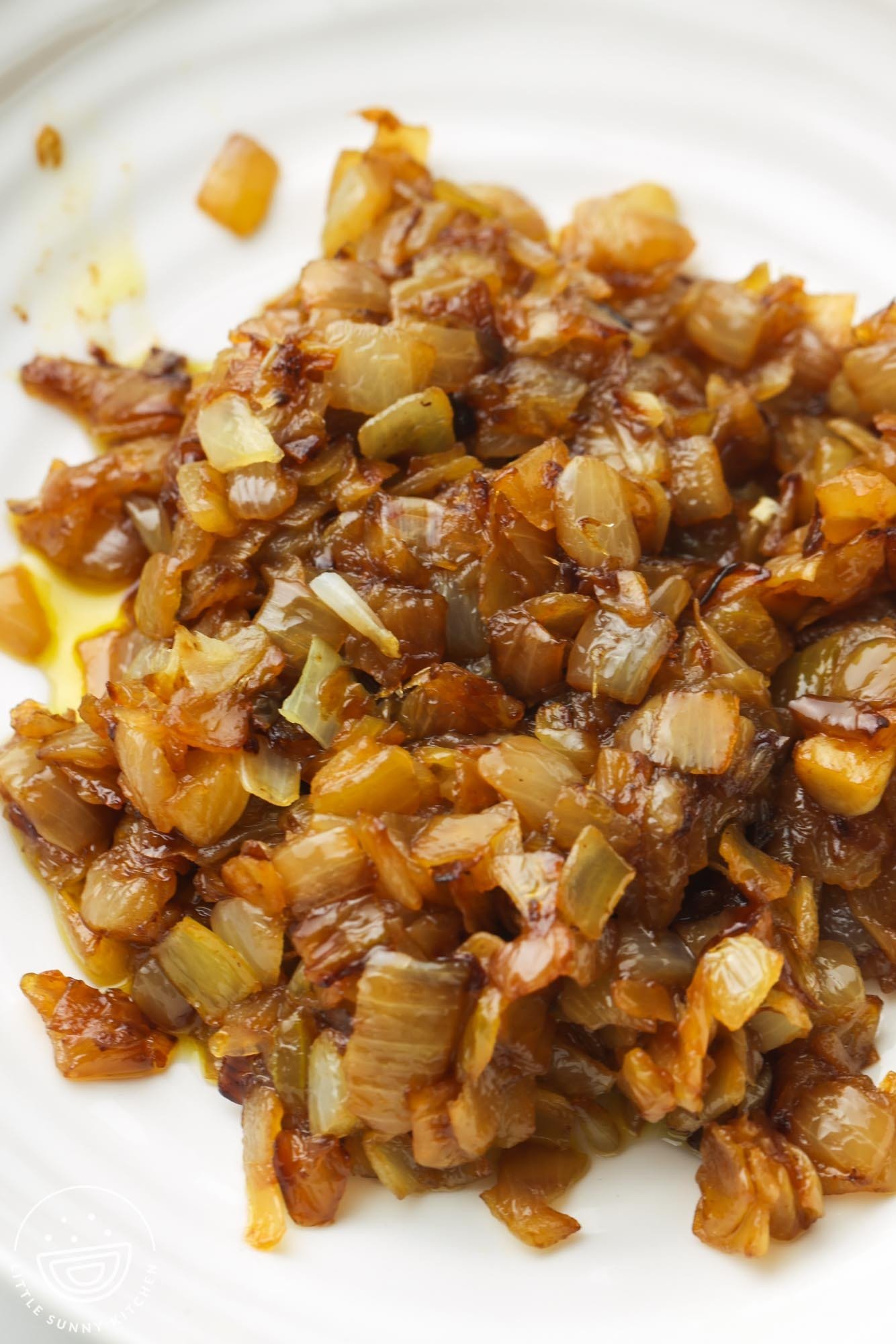 closeup of a pile of deeply caramelized diced onions on a white plate. 