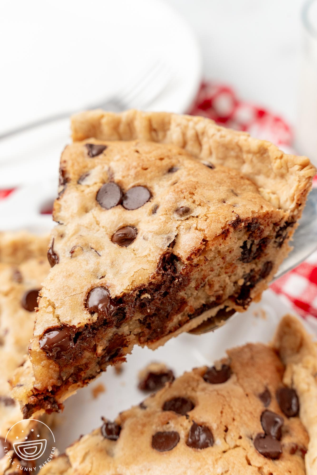A slice of chocolate chip cookie pie with chocolate chips lifted from the pan.