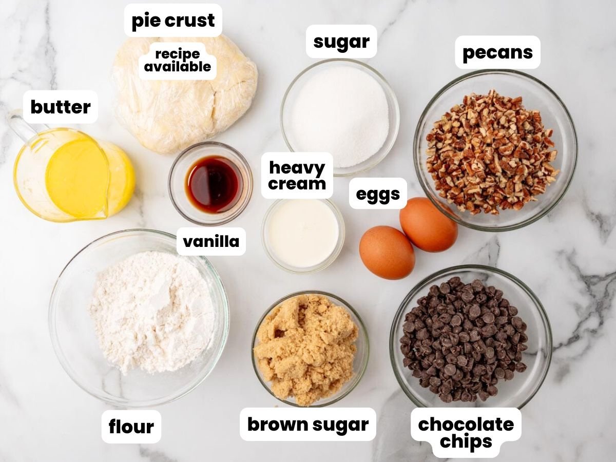 Ingredients for chocolate chip cookie pie including pecans and butter, all measured out and arranged on a marble counter.