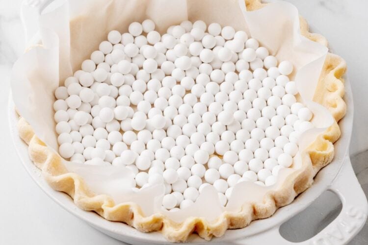 parchment paper and pie weights inside a fluted, unbaked pie crust.