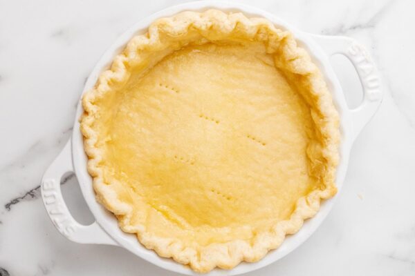 blind baked pie crust in a white ceramic pie plate.