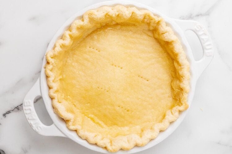blind baked pie crust in a white ceramic pie plate.
