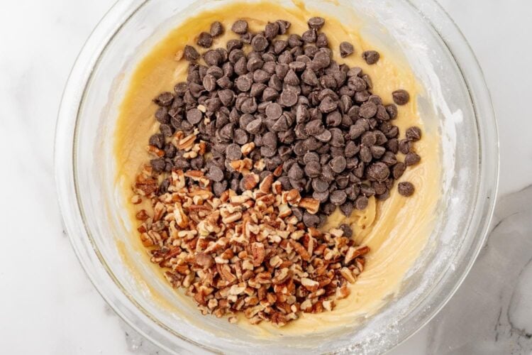 chopped pecans and chocolate chips added to a bowl of cookie dough pie filling.
