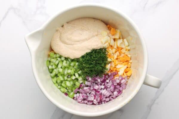 chopped eggs, cottage cheese dressing, fresh dill, diced onion and diced celery in a large ceramic mixing bowl