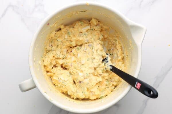 cottage cheese egg salad mixed in a ceramic bowl with a black spatula.