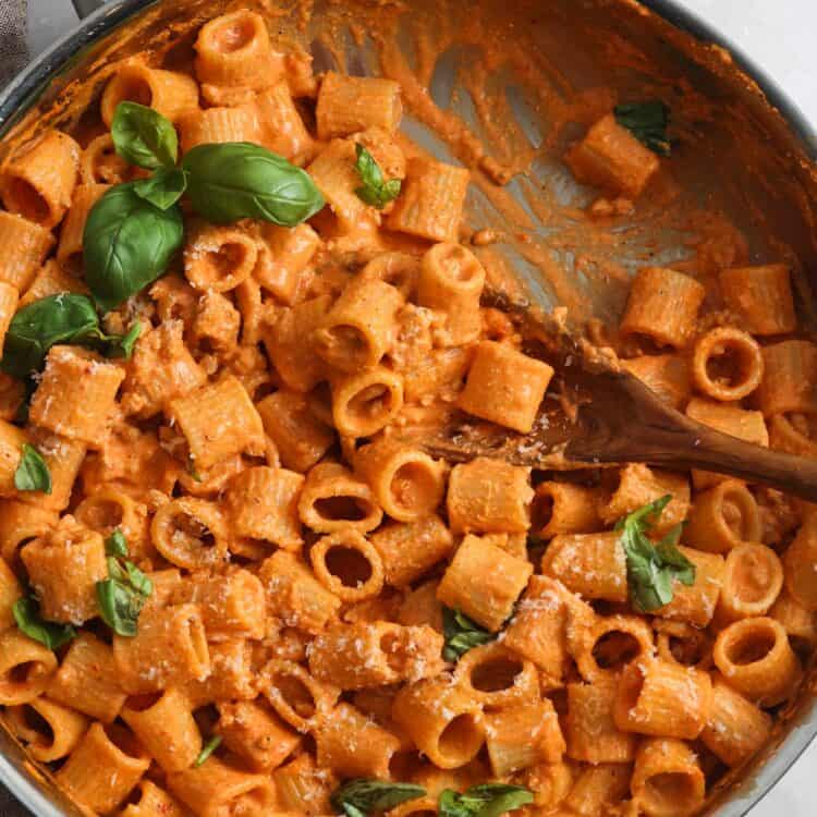 cottage cheese pasta sauce with roasted red bell pepper and chicken in a skillet, garnished with fresh basil leaves.
