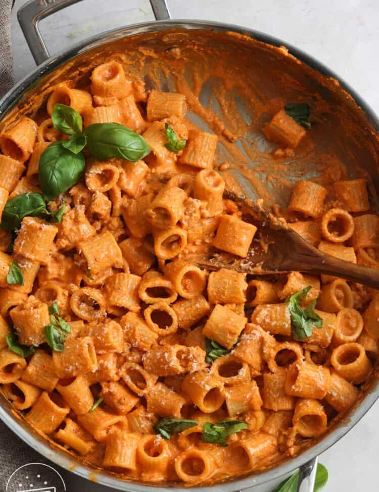 cottage cheese pasta sauce with roasted red bell pepper and chicken in a skillet, garnished with fresh basil leaves.