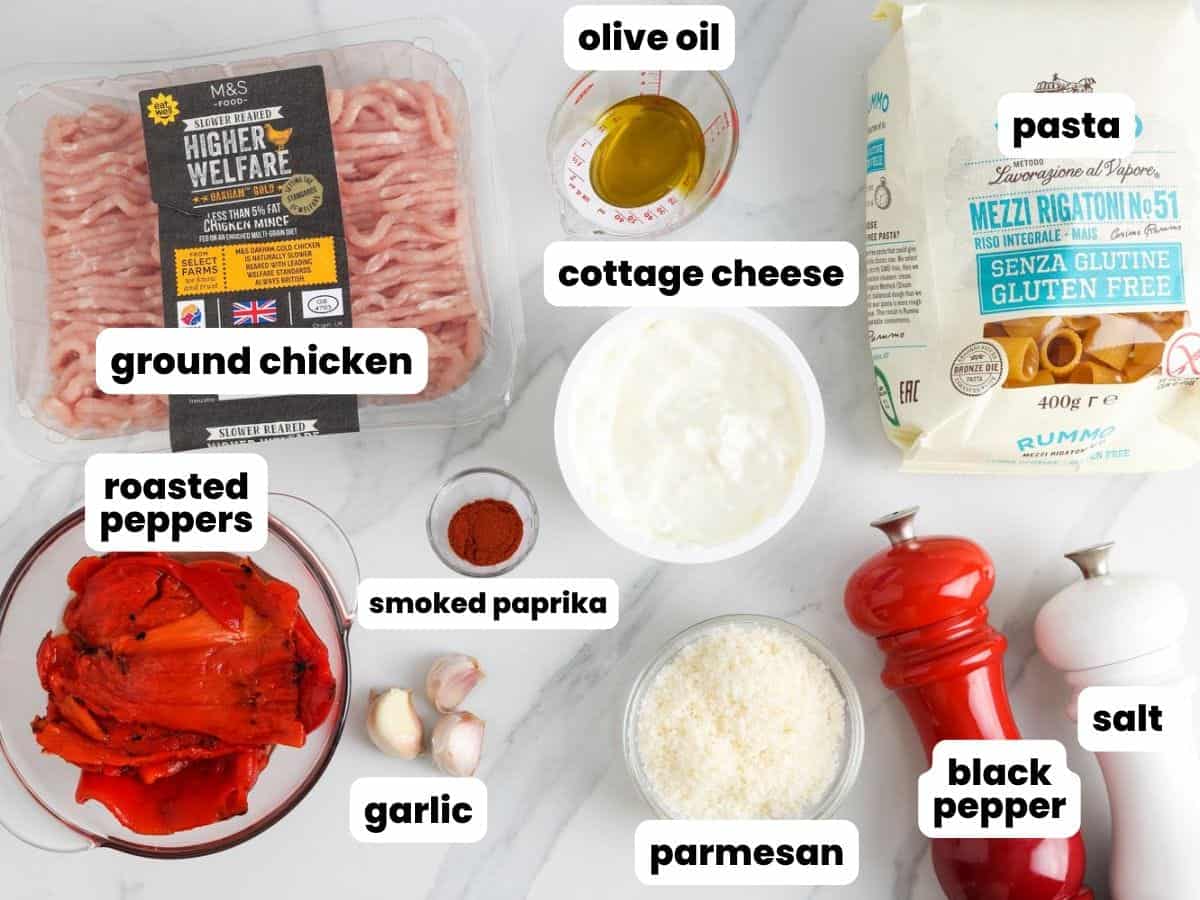 Ground chicken, roasted red peppers, cottage cheese, pasta, and seasonings arranged on a marble surface. These are the ingredients to make cottage cheese pasta sauce.