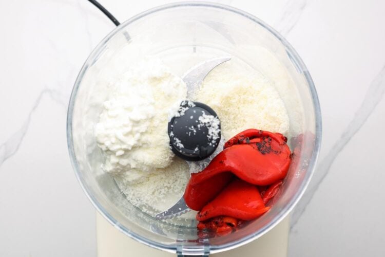 cottage cheese, parmesan cheese, and roasted red peppers in the bowl of a food processor.