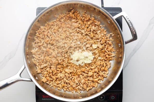 ground chicken cooked in a skillet with garlic.