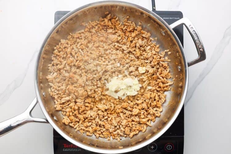 ground chicken cooked in a skillet with garlic.