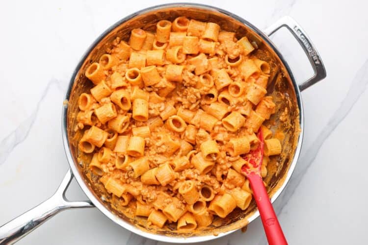orange tinted roasted red pepper cottage cheese pasta sauce coating pasta and ground chicken in a skillet.