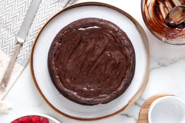 overhead view of a flourless chocolate cake with ganache spread over it.