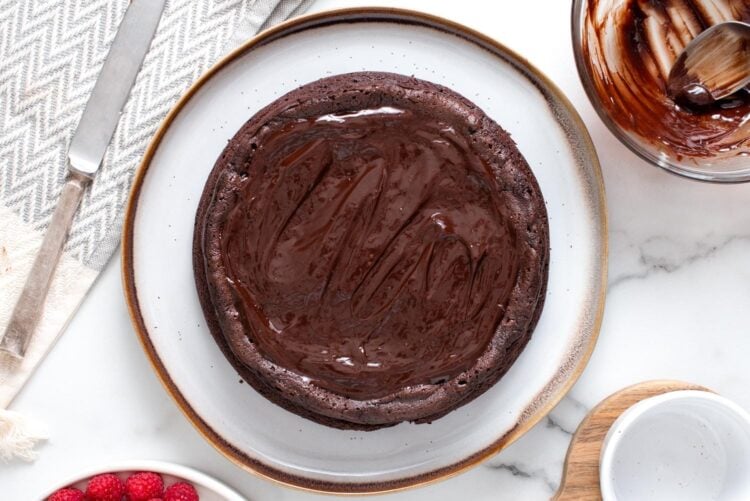 overhead view of a flourless chocolate cake with ganache spread over it.