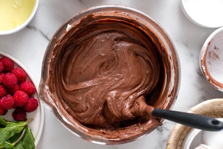 flourless chocolate cake batter stirred with a spatula in a large glass bowl.