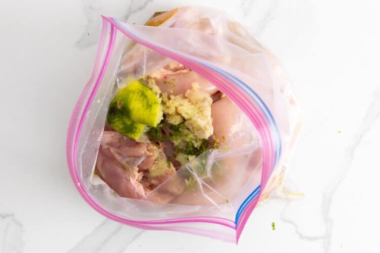 Chicken thighs in a ziplock bag with squeezed limes and seasonings for marinade.