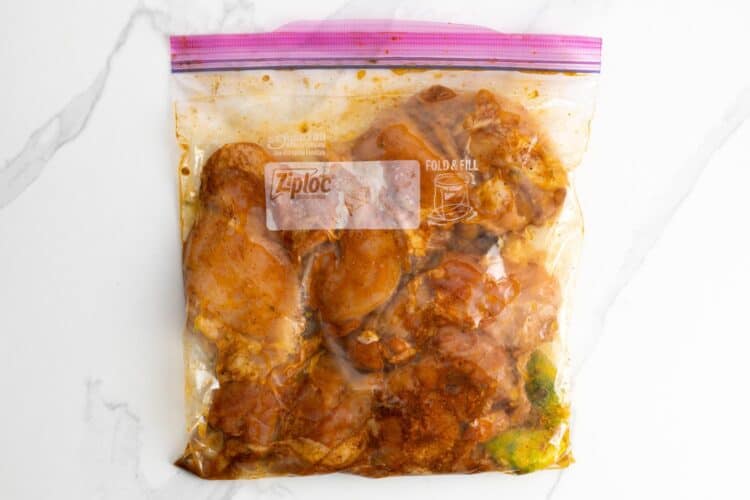 chili lime marinated chicken thighs in a ziploc bag that is on a marble counter.