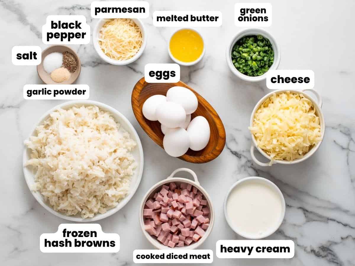 Ingredients for making quiche with a hash brown crust, measured in small bowls and arranged on a marble counter.