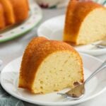 Slices of yogurt pound cake on white dessert plates with small silver forks.