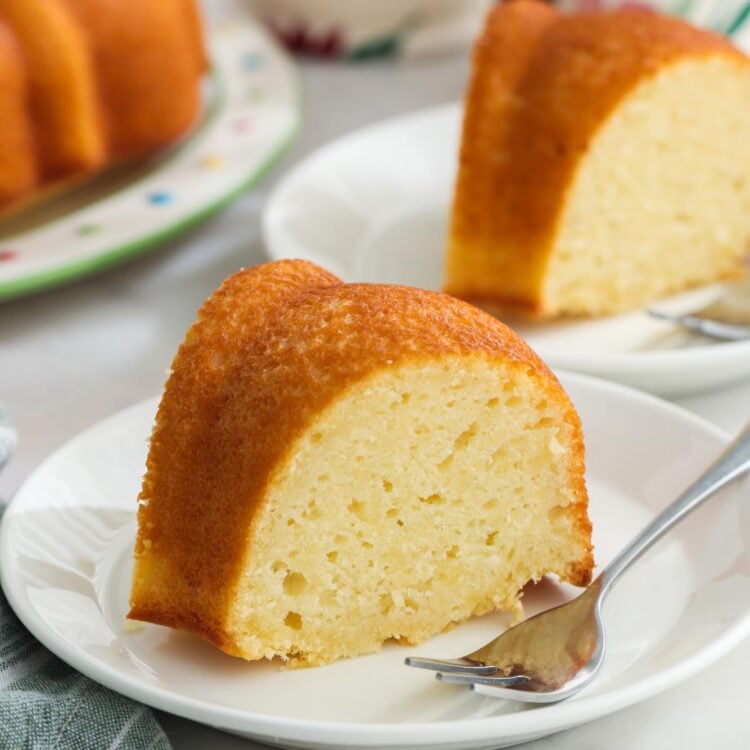 Slices of yogurt pound cake on white dessert plates with small silver forks.