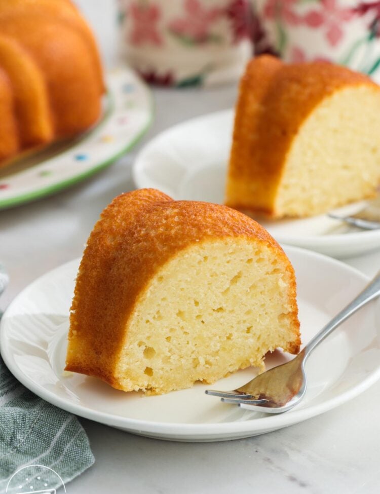 Slices of yogurt pound cake on white dessert plates with small silver forks.