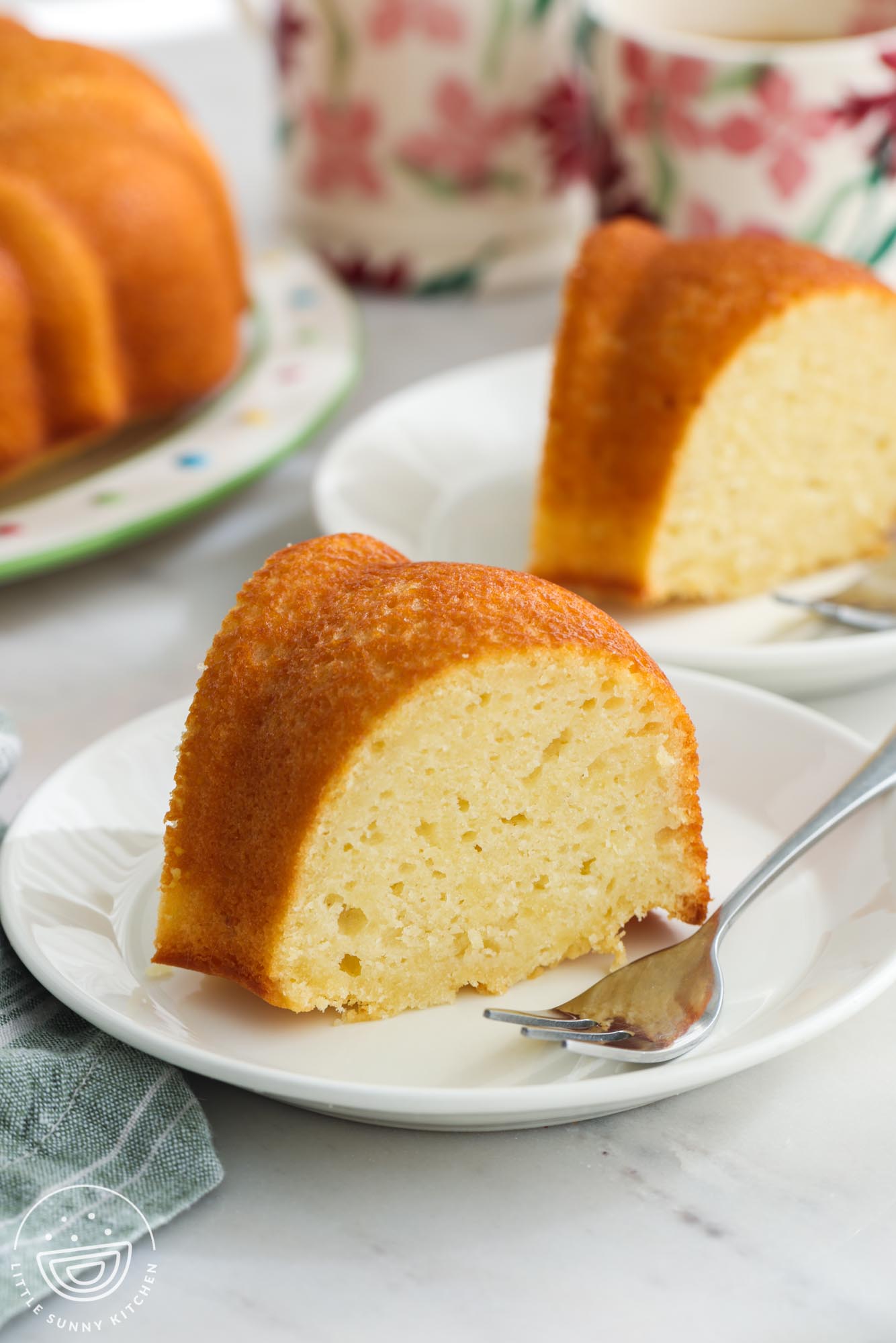 Slices of yogurt pound cake on white dessert plates with small silver forks.