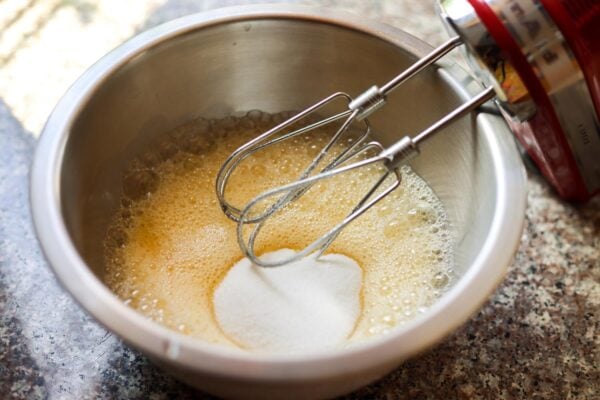 Sugar added to a bowl of frothy eggs.