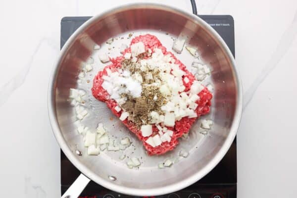 ground beef, seasonings, and diced onions in a skillet.