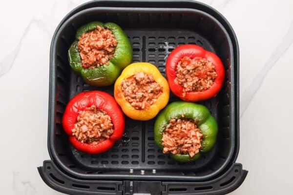 stuffed bell peppers in an air fryer basket.