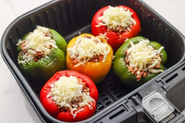 cheese added to stuffed colorful peppers in an air fryer.