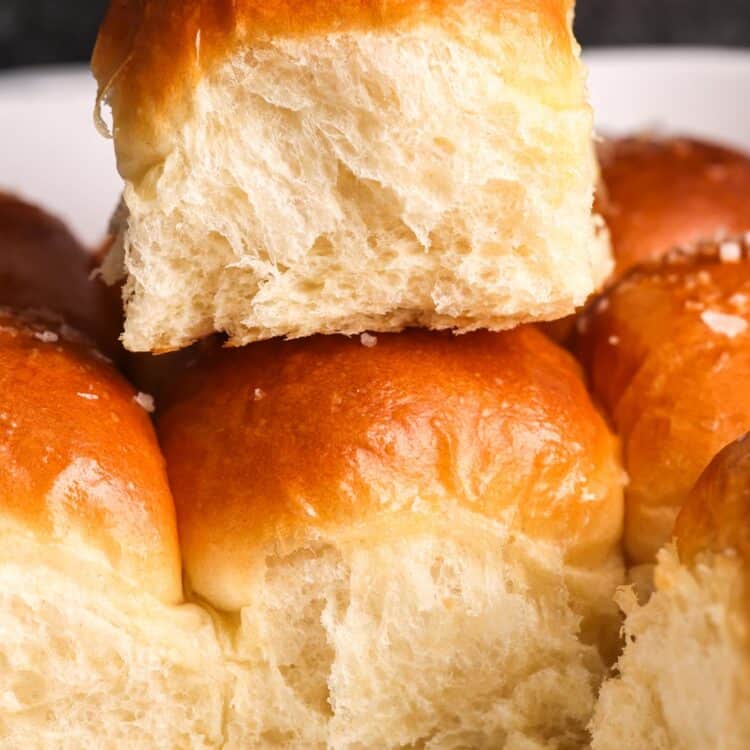 a fluffy dinner roll on top of the other dinner rolls.