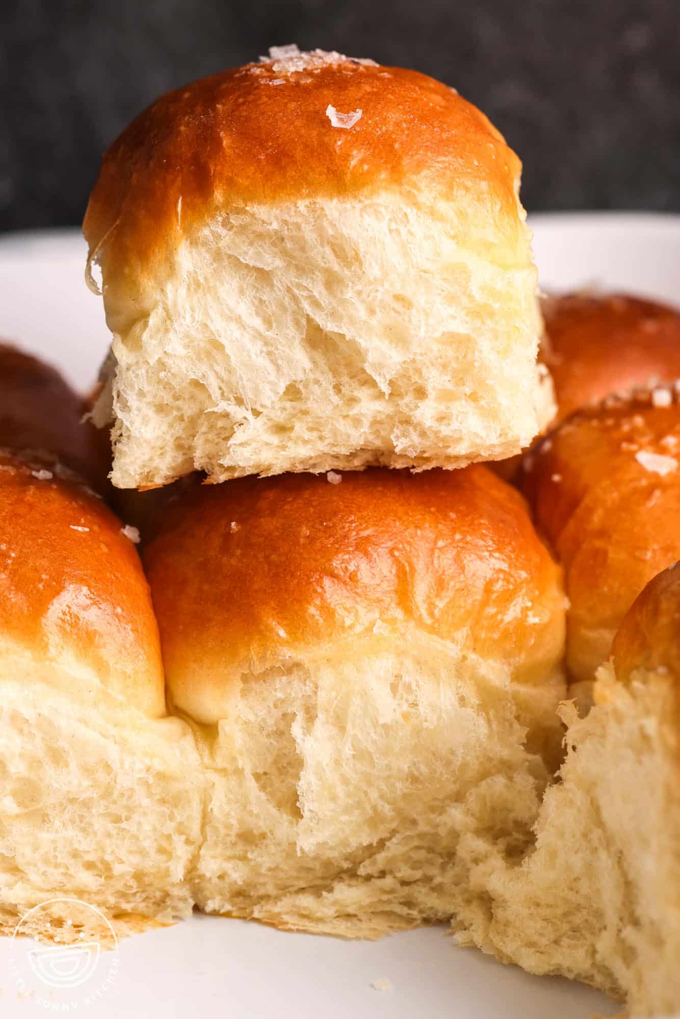 a fluffy dinner roll on top of the other dinner rolls.