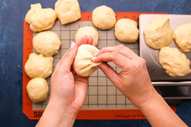 hands dividing dough into portions and forming into rolls using a pinching motion.