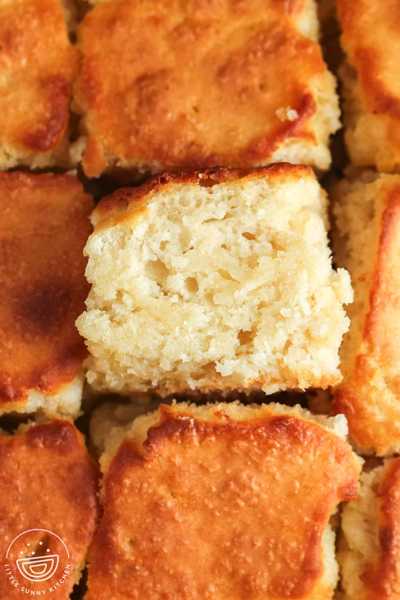 a pan of butter swim biscuits. One is turned sideways to show to buttery dense interior.