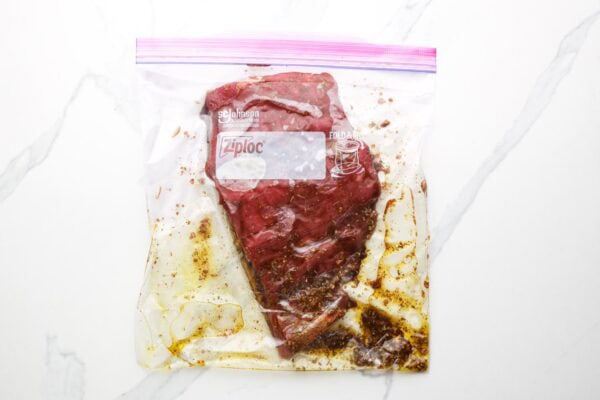 A flank steak in a ziplock bag, marinating in a balsamic honey sauce.