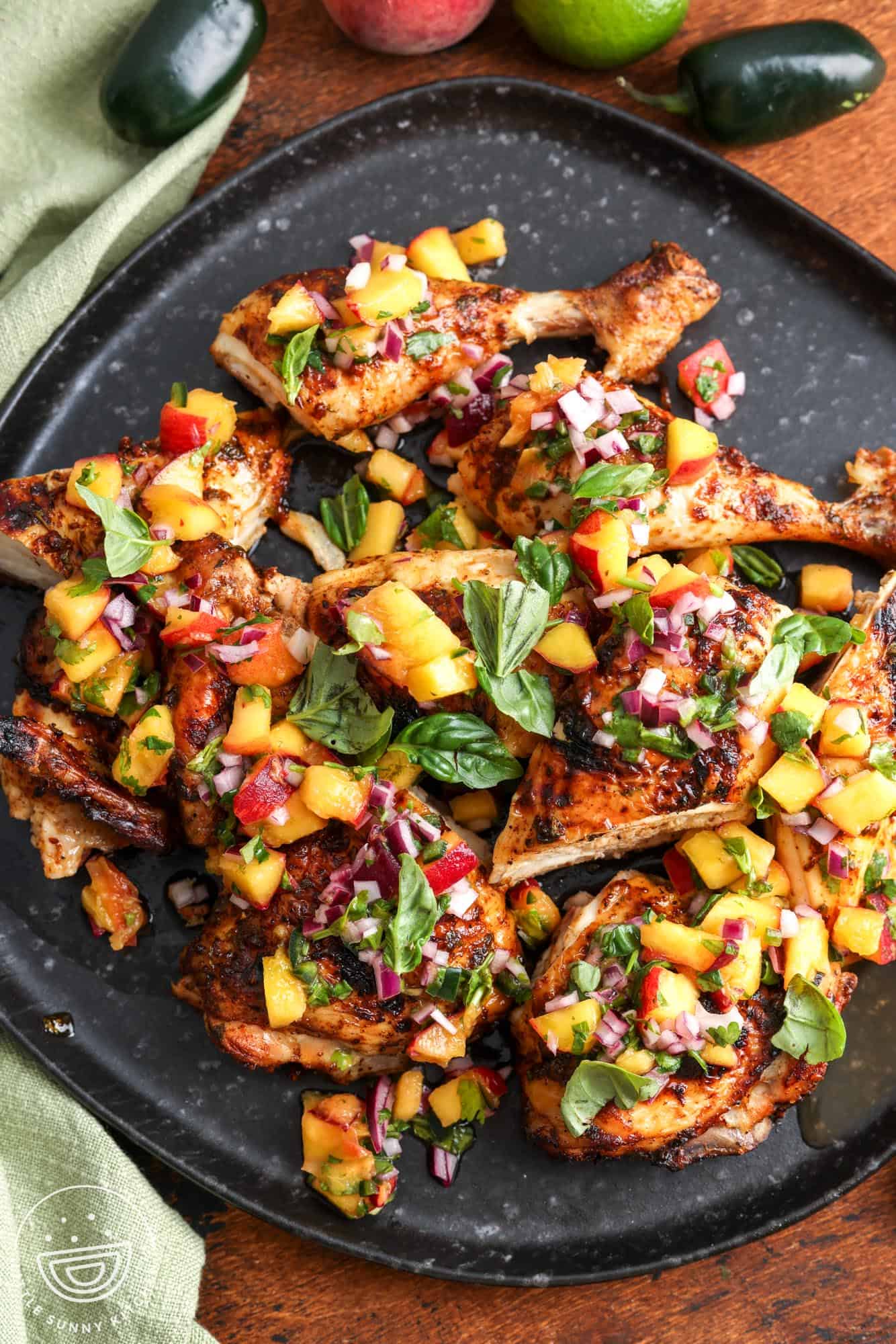 a platter of grilled cilantro lime chicken with peach salsa on top.