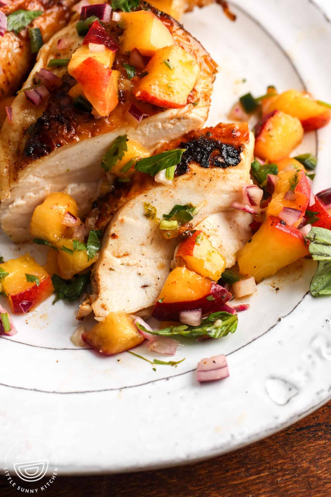 closeup of juicy sliced grilled chicken with peach salsa.