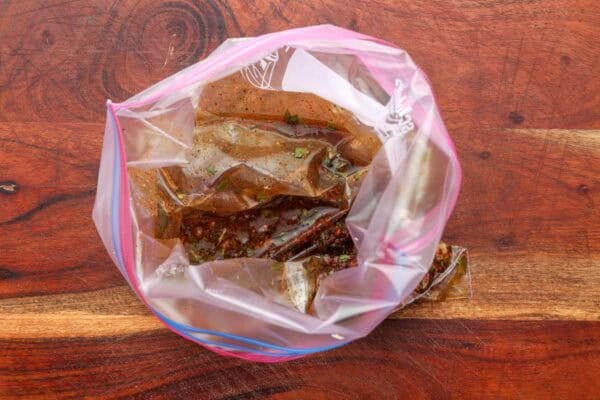 cilantro lime marinade for chicken in a plastic zip top bag, set on a wooden counter.