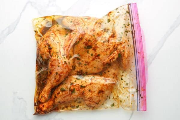chicken pieces marinating in a cilantro lime mixture in a ziplock bag.