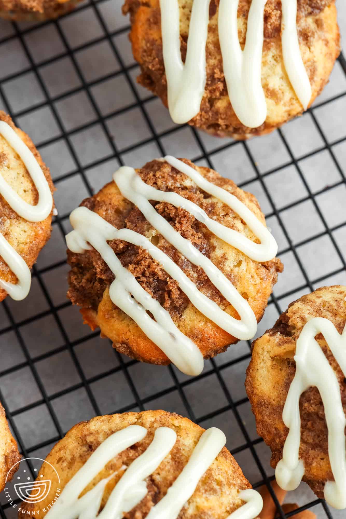 overhead view of cinnamon roll muffins topped with frosting, sitting on a wire rack.