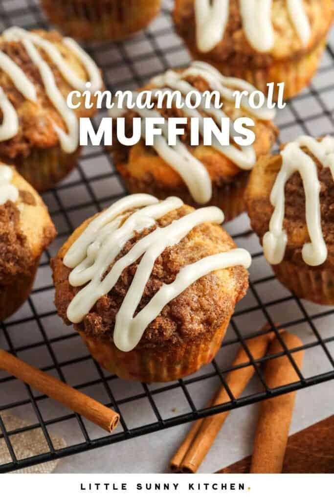 Cinnamon streusel topped muffins with a frosting glaze, set on a wire rack. Text overlay says "cinnamon roll muffins"