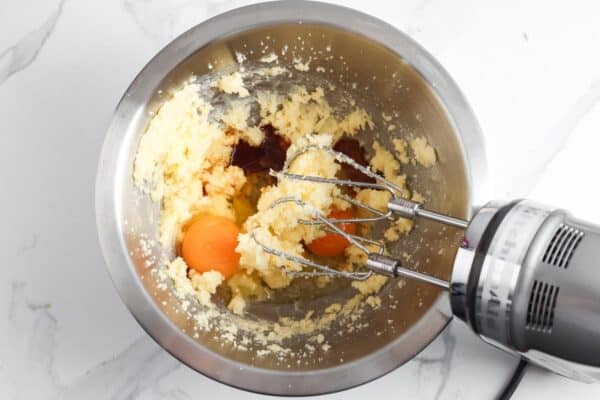 eggs mixed with creamed butter and sugar in a metal bowl, using an electric hand mixer.