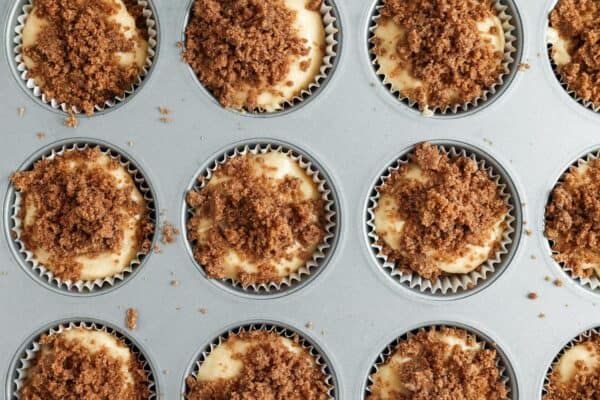 Cinnamon roll muffins in a pan topped with cinnamon sugar mixture.