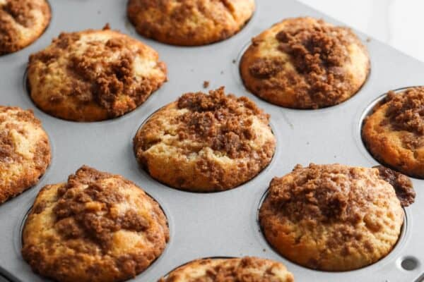 baked cinnamon roll muffins in a metal muffin pan.