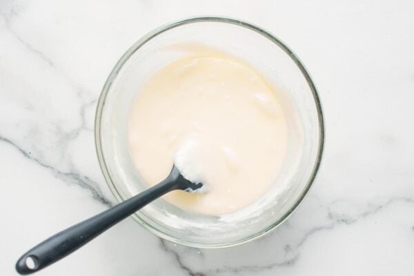 white chocolate and heavy cream melted together in a small glass bowl.