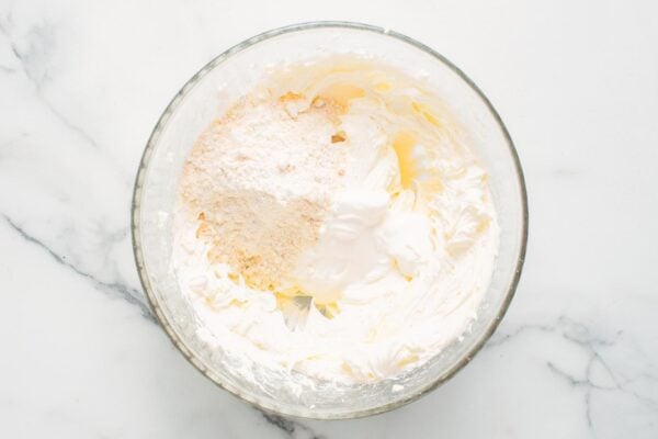 cream cheese, powdered sugar, and cake mix combined in a large glass bowl to make no bake cheesecake.