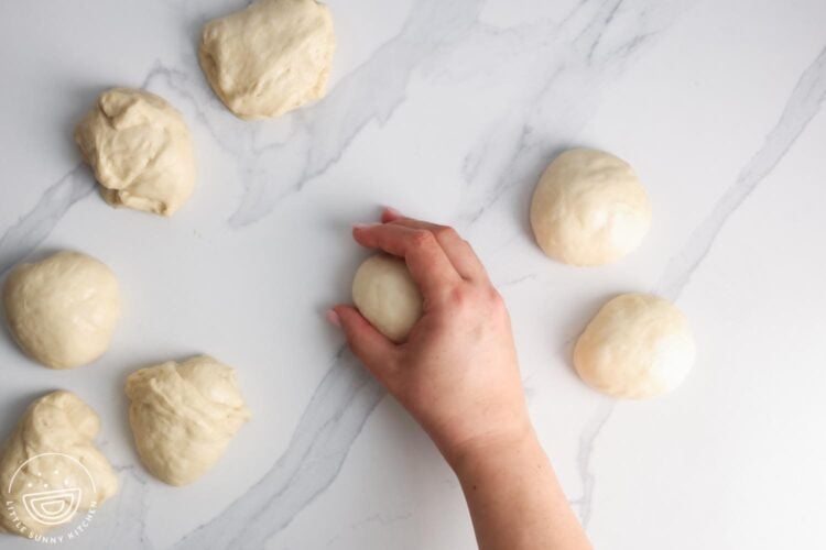 portions of dough shaped by hand into round hamburger buns.