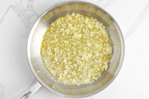 diced yellow onion sauteeing in a skillet.